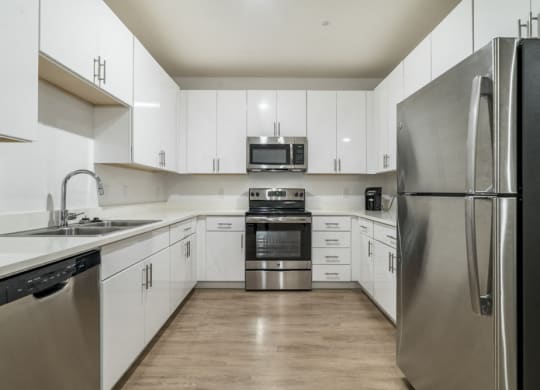 Contemporary kitchen with white cabinetry, quartz countertops and stainless steel appliances at The Conrad
