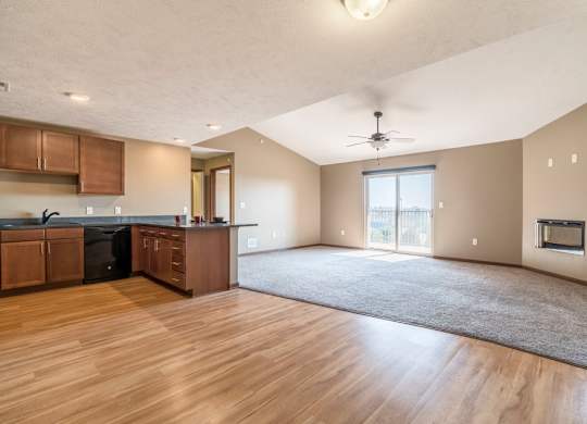 A spacious kitchen with wooden floors and a ceiling fan.