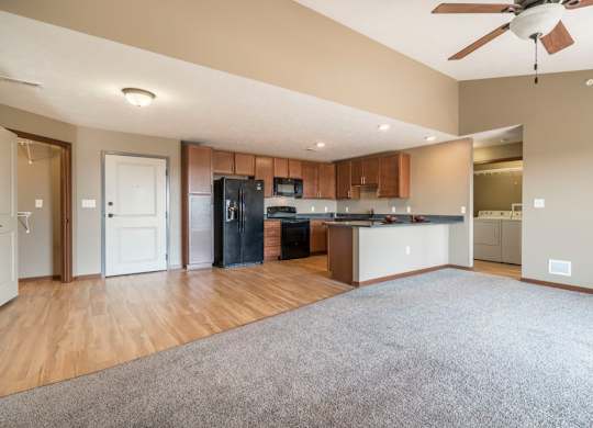A spacious kitchen with wooden floors and a ceiling fan.