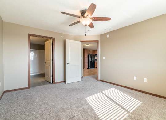 A room with a ceiling fan and carpeted floor.