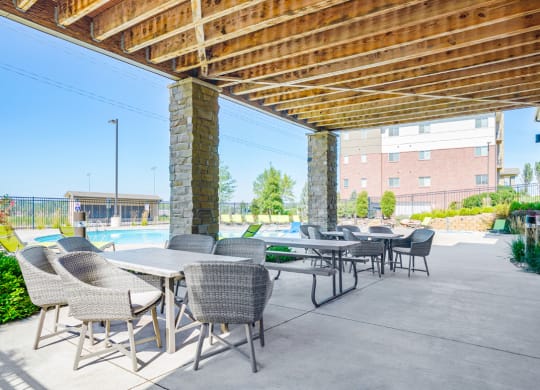 a patio with tables and chairs and next to the community pool