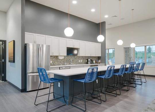 Modern resident lounge kitchen with expansive island seating, white cabinets, mosaic tile backsplash, and contemporary finishes.