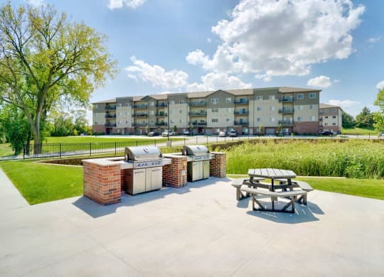 Outdoor grilling area with two stainless steel grills and a round picnic table