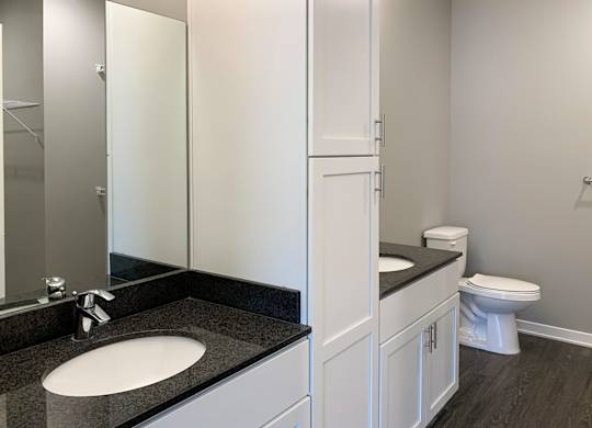 A bathroom with a sink, toilet, and a mirror.