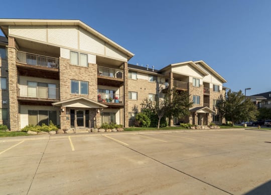 a three-story apartment building with a parking lot in front of it