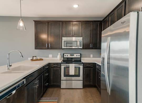 A modern kitchen with dark wood cabinets and stainless steel appliances.