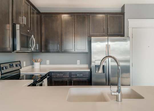 A modern kitchen with dark brown cabinets and stainless steel appliances.