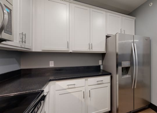 a kitchen with white cabinets and a stainless steel refrigerator