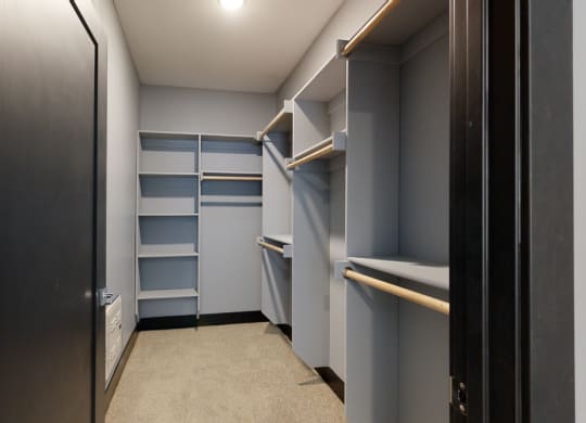 a walk in closet with gray walls and shelves