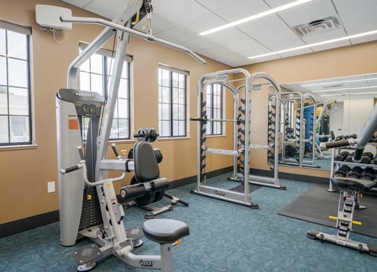 a fitness center with an exercise machine and a free weight bar rack