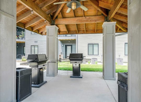 a covered outdoor grill station with two grills and a ceiling fan