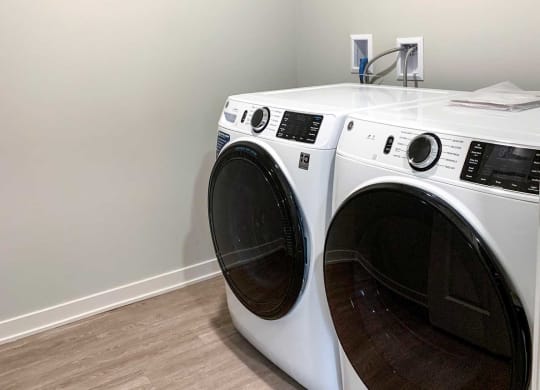 a washer and dryer in a laundry room with a wooden floor