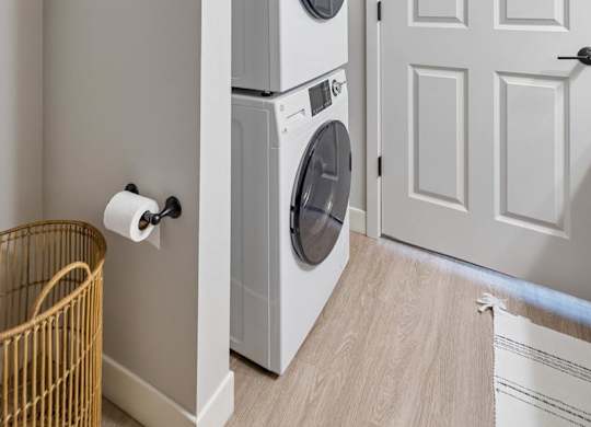 Apartment laundry area with stacked washer and dryer beside paneled doors.