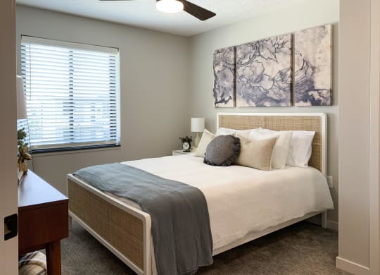 Furnished bedroom with ceiling fan and marbled art above the bed