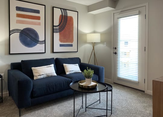 a living room with a blue couch and two paintings on the wall