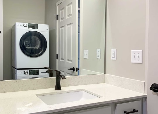 a bathroom with a sink, cabinets, and a stackable washer and dryer