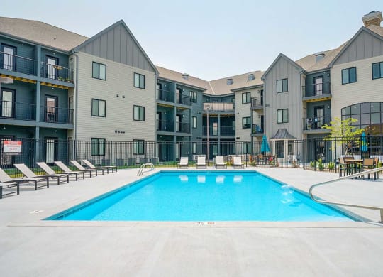 a resort style swimming pool with lounge charge surrounding it, in the center of an apartment courtyard