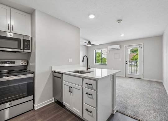 Open apartment living area with kitchen island, stainless steel appliances, and private balcony access.