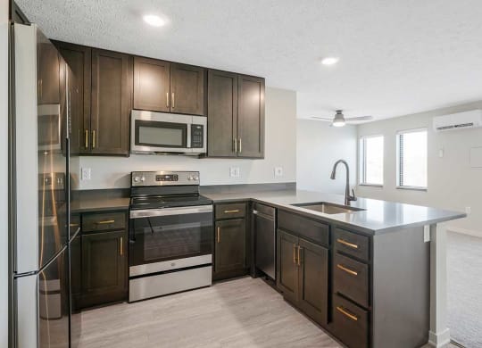 A kitchen with stainless steel appliances and dark cabinets