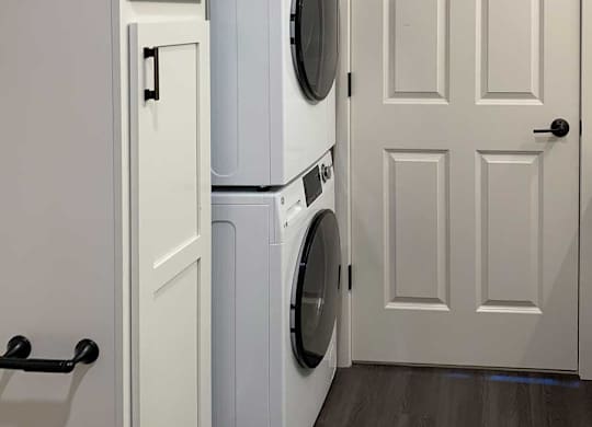 a bathroom with a linen storage cabnet and a stackable washer and dryer