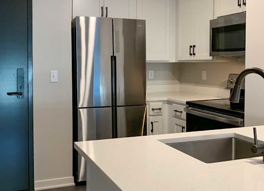a modern kitchen with white cabinets, quartz countertops, and stainless steel appliances