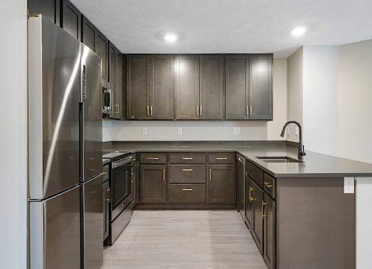 A U-shaped kitchen featuring dark cabinets and stainless steel appliances