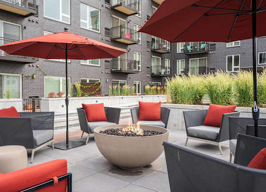 a patio with red couches and umbrellas around a fire pit in the zen garden