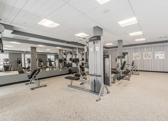 View of fitness center with weightlifting machines and mirrors at The Preserve apartments in Bloomington