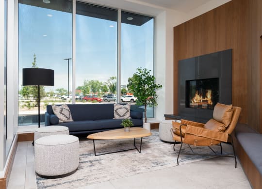 Lounging space with seating next to a fireplace and large floor to ceiling window.