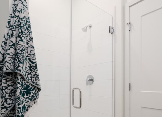 Walk in shower with glass door and towel hanging on rack to the right