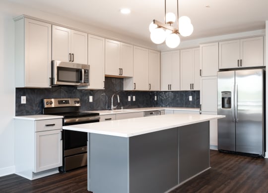 Beautiful white kitchen with matching stainless steel appliances and large kitchen island.