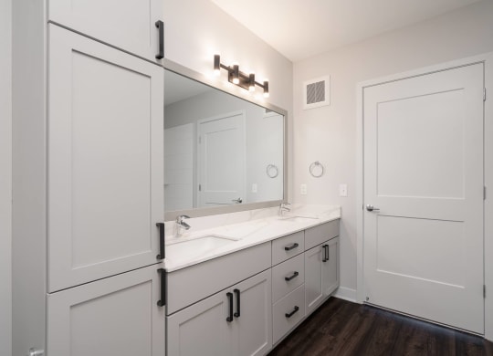 large white double vanity with large mirror and tall storage cabinet on the right