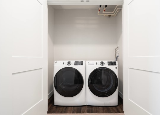 washer and dryer side by side in laundry closet with doors open