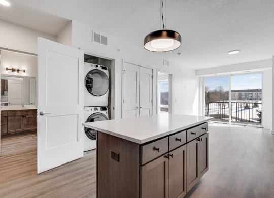 Kitchen island counter space with hidden stacked washer and dryer at The Rowan in Eagan Minnesota