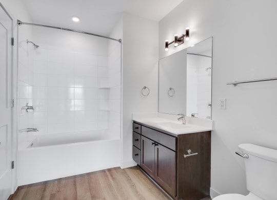 Bathroom with dark brown vanity and linen cabinet for storage and large mirror at The Rowan in Eagan Minnesota