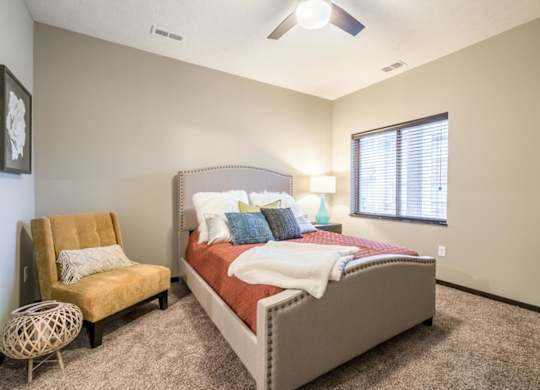A bedroom with a bed, chair, and window.