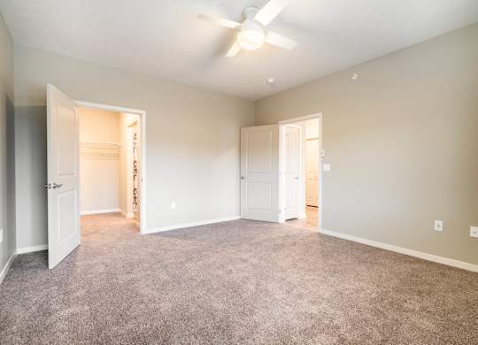 A spacious room with a ceiling fan and carpeted floor.