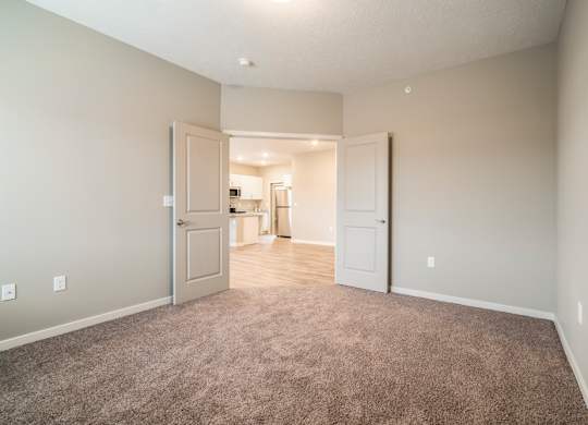 A room with a carpeted floor and two doors.