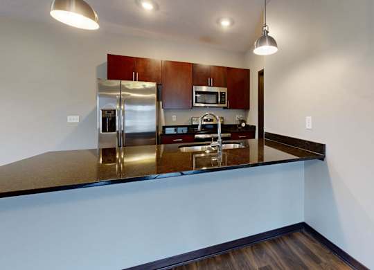 A kitchen with a stainless steel refrigerator and cherry wood cabinets.