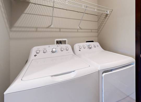 A white washer and dryer with a shelf above them in small laundry room