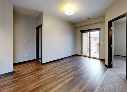 A room with wooden flooring and a sliding glass door.