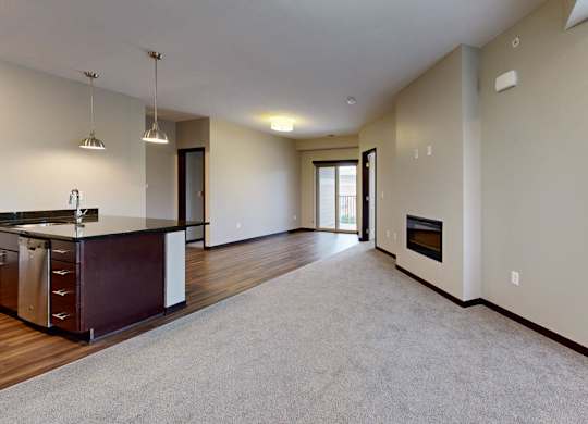 A spacious living room with a kitchen area and a fireplace.