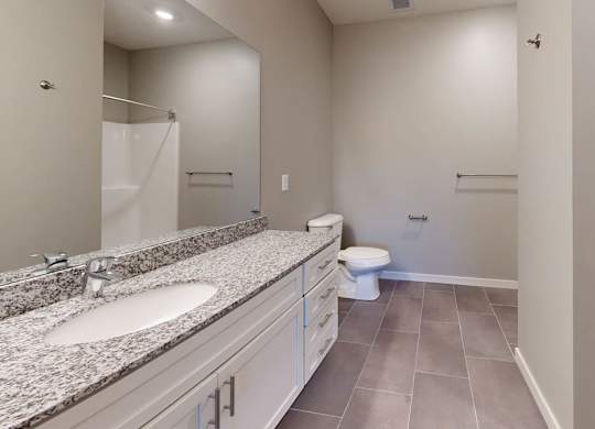A bathroom with a toilet, sink, and shower, plus an attached closet.