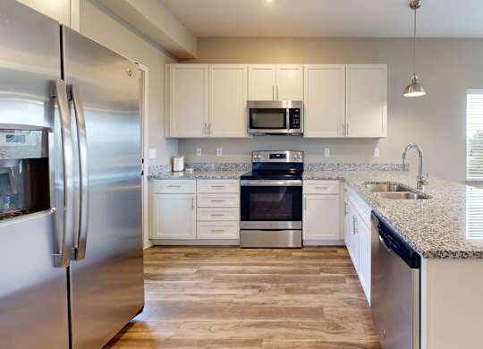 A modern kitchen with stainless steel appliances and wooden flooring.