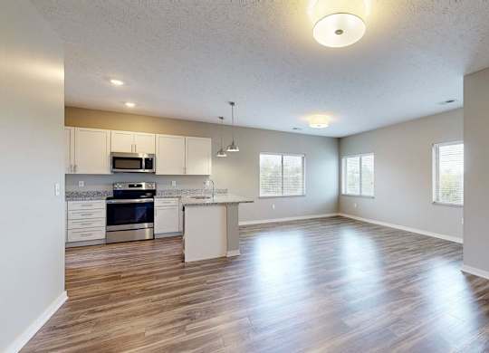 A spacious kitchen and living room with wood floors and white walls.