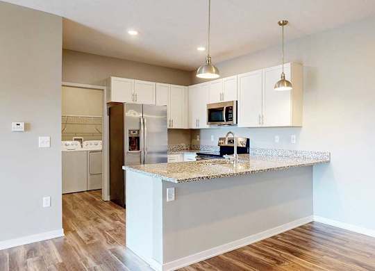 A kitchen with white wooden cabinets, granite countertops, stainless steel appliances, and a peninsula countertop.