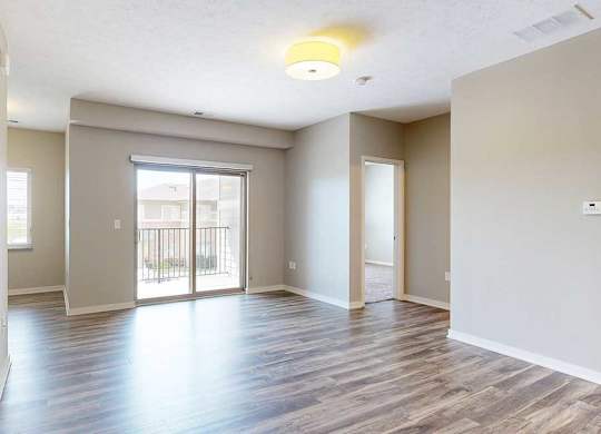 A living room with hardwood-style flooring and a sliding glass door to a balcony.