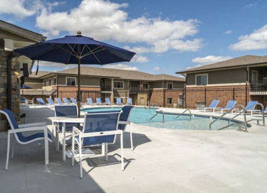 Resort-style pool with chairs and umbrellas at The Villas at Falling Waters in west Omaha