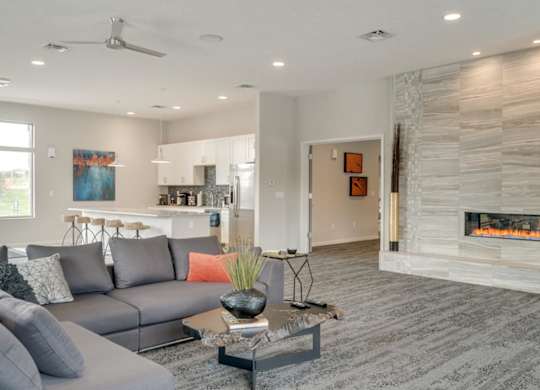 A modern clubhouse great room with a grey sofa and a fireplace.