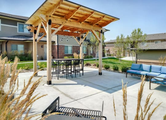 Outdoor patio with table and couch, covered by wooden pergola